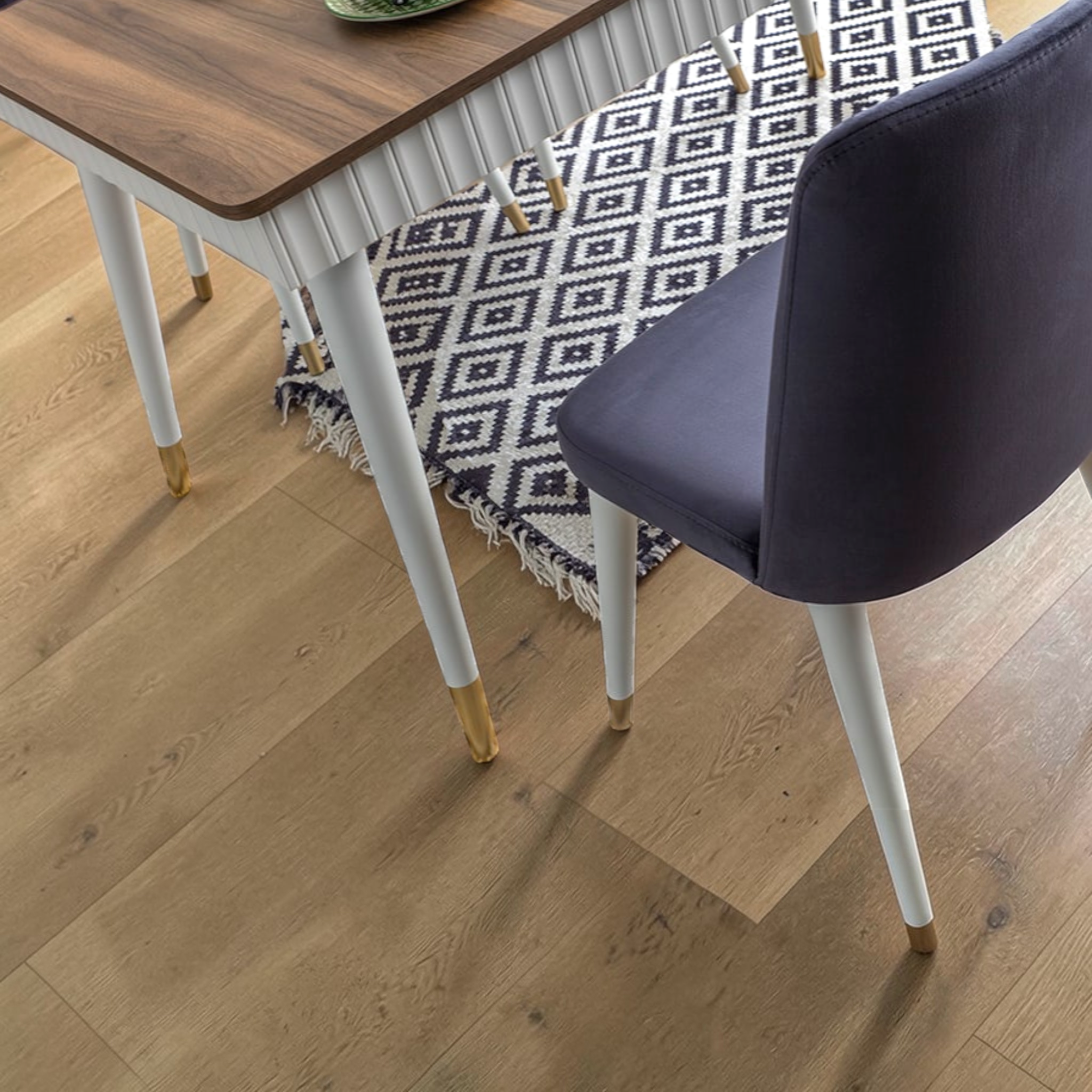 Dining table with a patterned tablecloth and a chair on a wooden floor